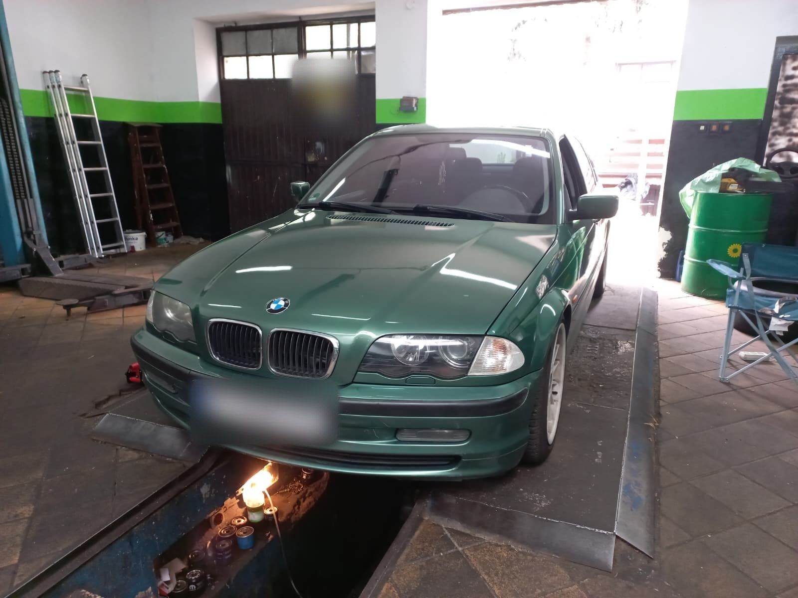 Zielone BMW serii 3 (E46) nad kanałem w warsztacie