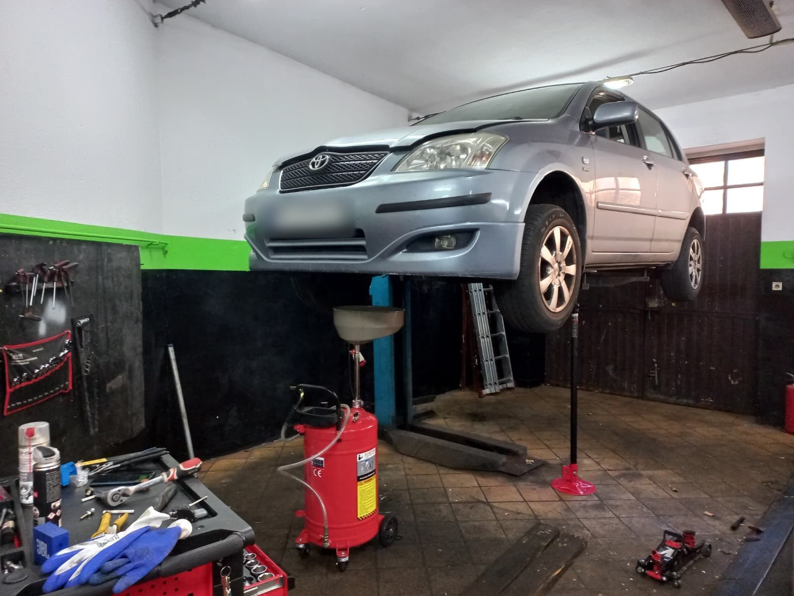 Toyota Corolla na podnośniku podczas wymiany oleju, pod autem zlewarka